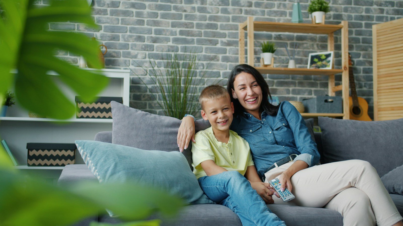 A mother and her young son laughing together on a sofa at home